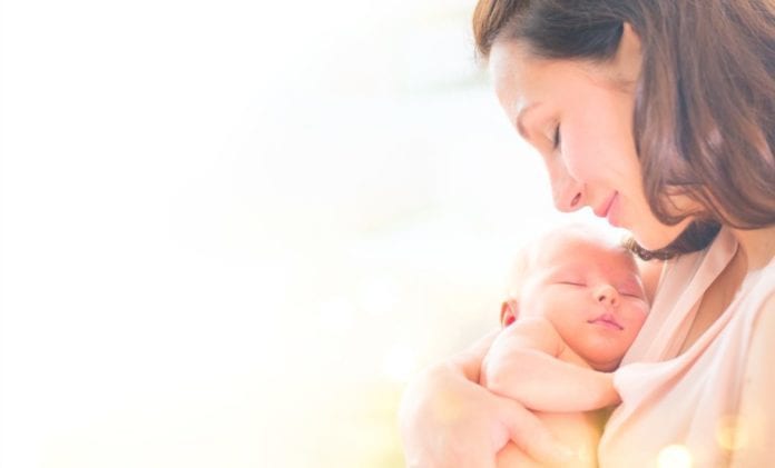 Mother and her newborn baby together. Happy mother and baby kissing and hugging. Maternity concept. Parenthood